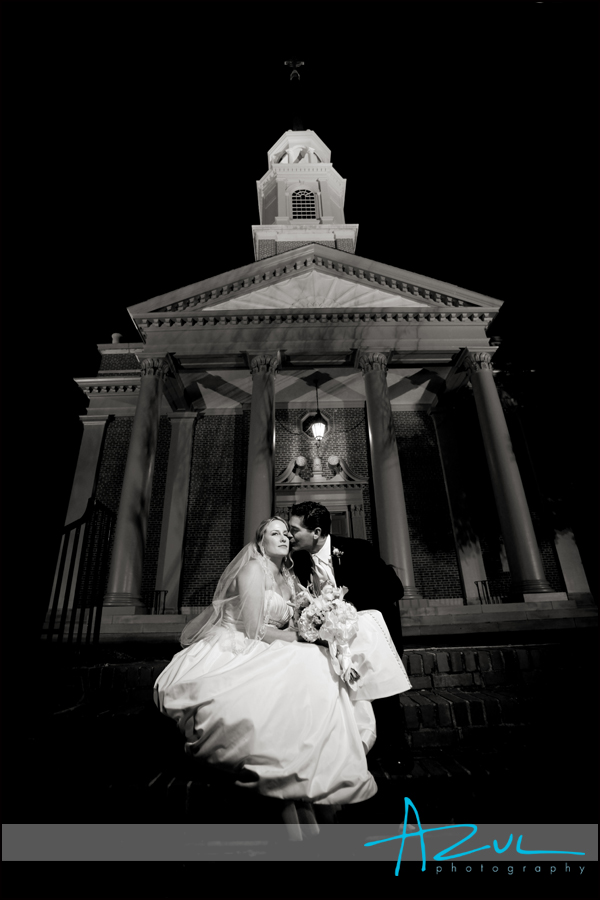 The bride and groom sit on the front steps of the church and share a kiss before heading to the reception.